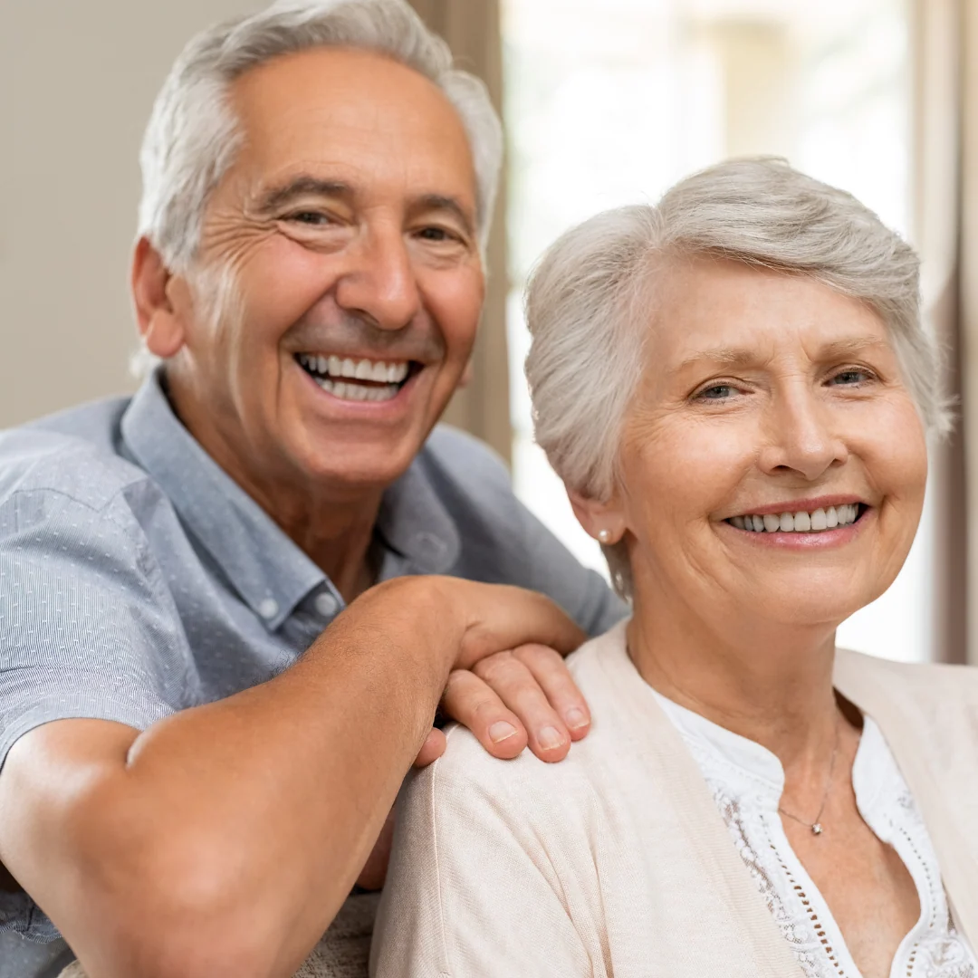 Senior couple smiling after dental implants in Porto for US seniors